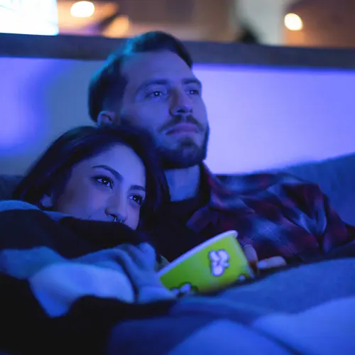 en mann og en kvinne sitter på en sofa og ser på tv.