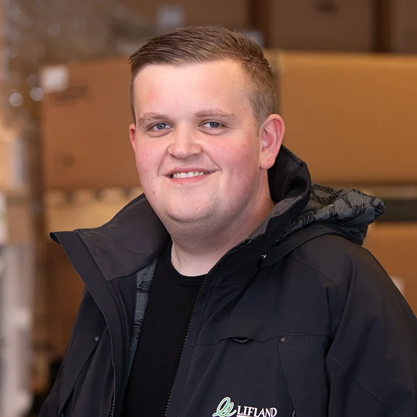 En ung mann, Pål Johansen, med kort hår smilende til kamera, ikledd en svart jakke med logoen «liftland» brodert i grønt.
