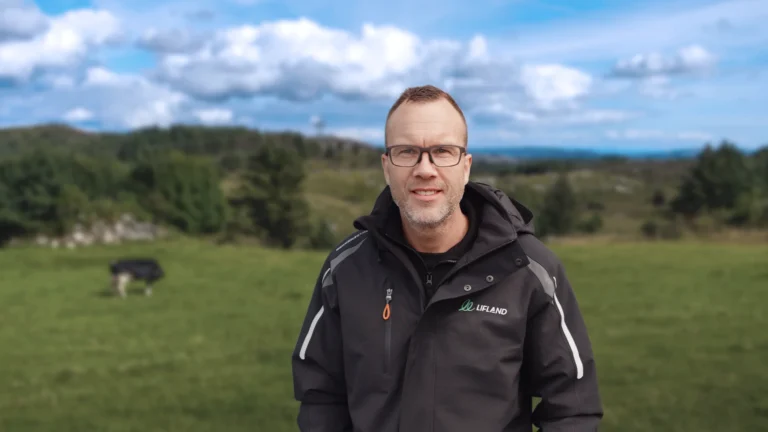En mann med briller og svart jakke står på en gresslette med trær og skyer i bakgrunnen. André Granrud er ny salgskonsulent i Lifland.
