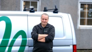 Knut Laursen står med armene i kors foran en hvit servicebil.