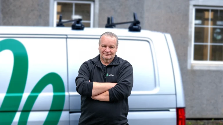 Knut Laursen står med armene i kors foran en hvit servicebil.